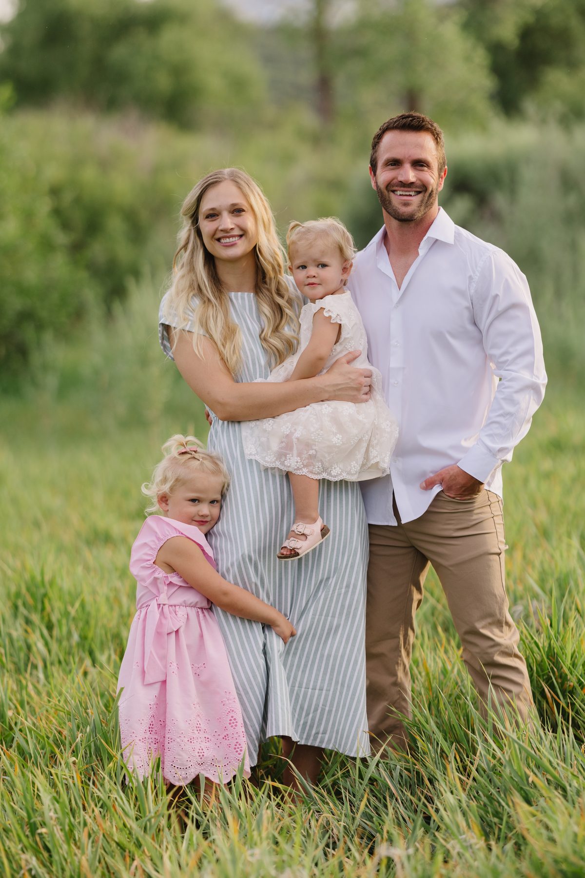 Britain and Nicole Sorensen standing in a grassy field with their two young daughters