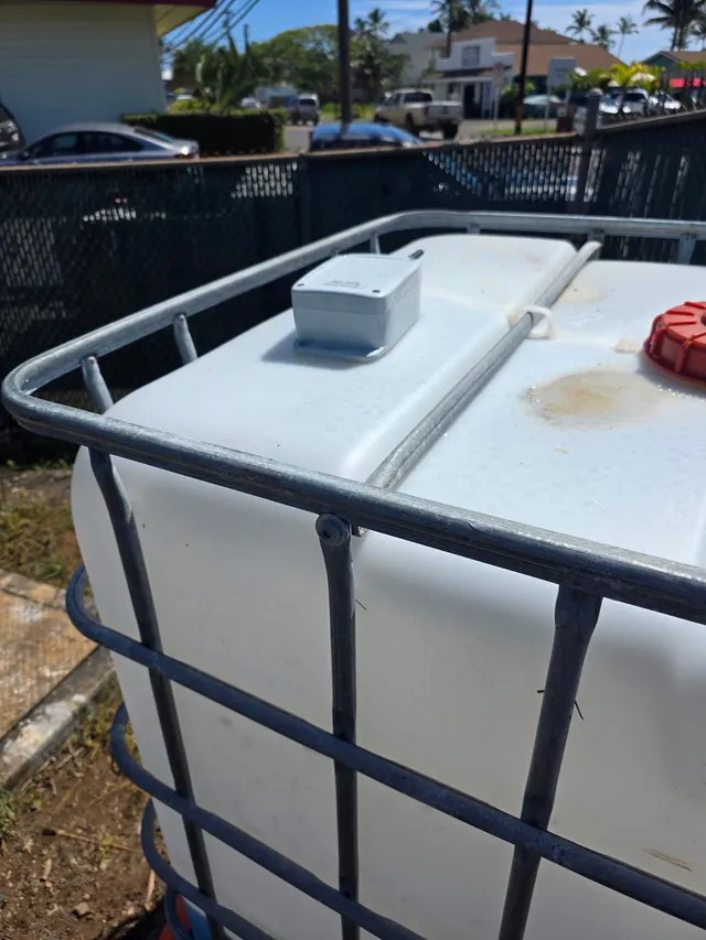 Close-up of a Meterra ultrasonic tank level sensor mounted on the lid of an IBC tote dosing tank in Hawaii