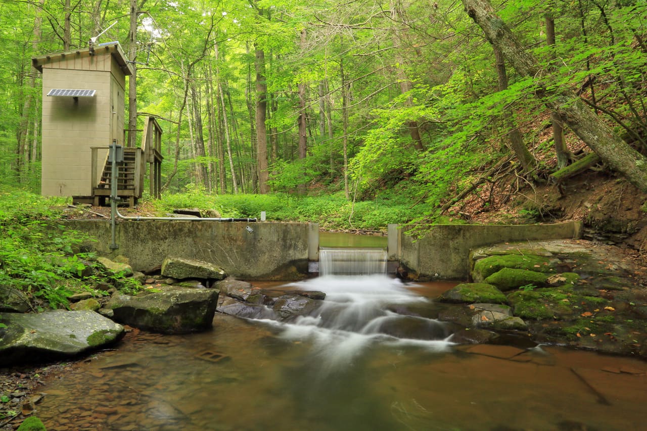 USGS streamgage station and concrete measuring weir on a forested creek