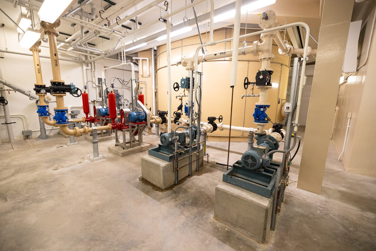 Pumps, valves, and painted piping inside a clean wastewater pump room