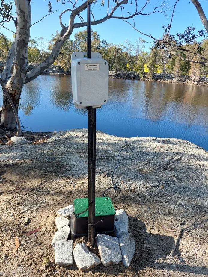 Communications unit on a post at the edge of a dam with the cable running into the water