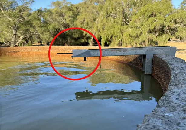 Tank level sensor mounted on a beam across an open concrete tank, circled in red
