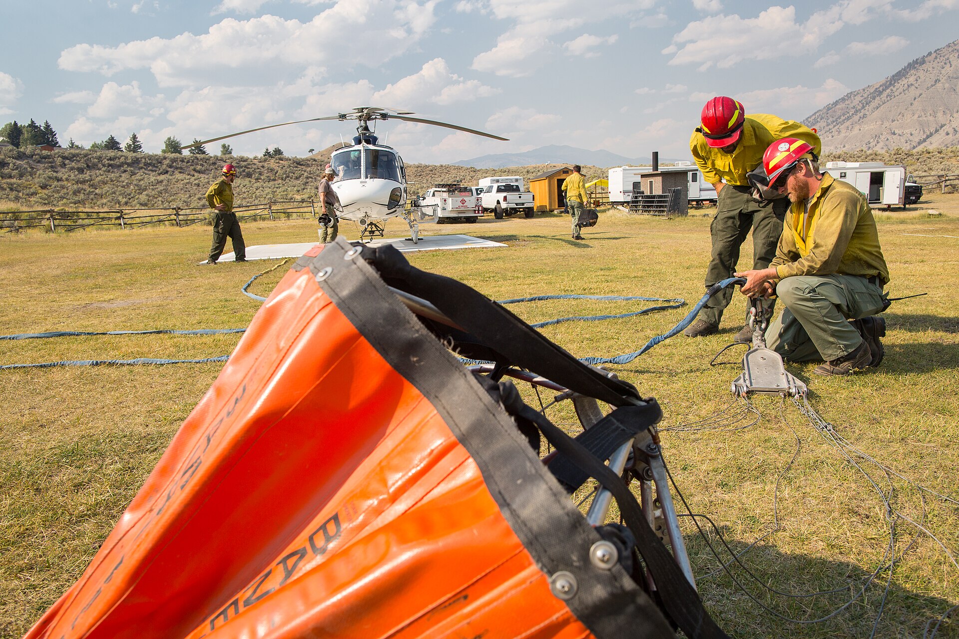 Helitack crew rigging a helicopter with a Bambi bucket for water drops during wildfire operations